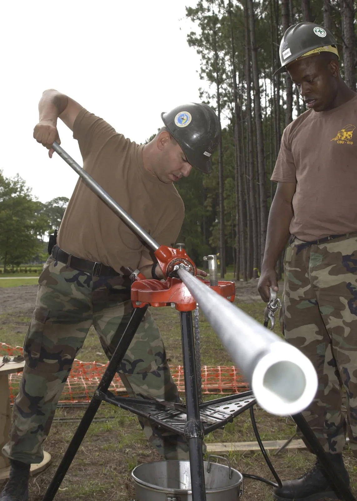 A U.S. Navy construction electrician cuts and fits wiring on a job