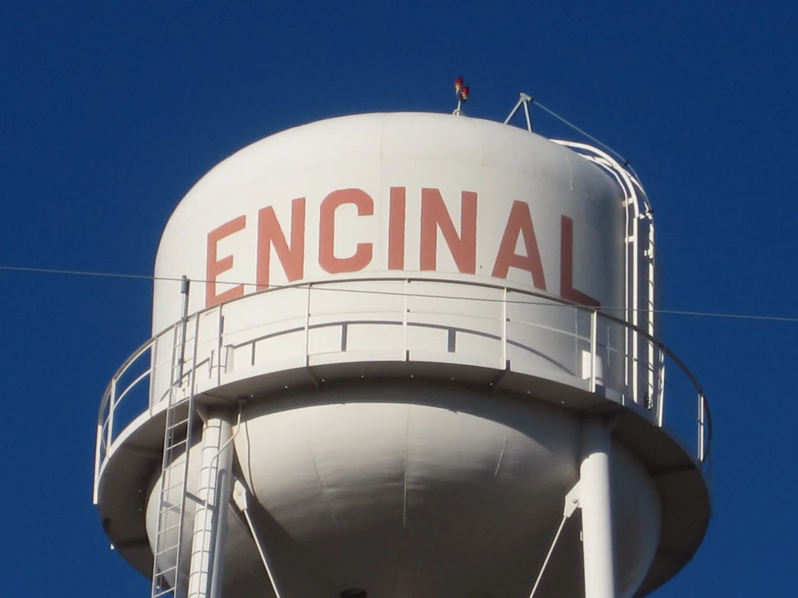 The white Encinal, Texas water tower with red lettering against a blue sky