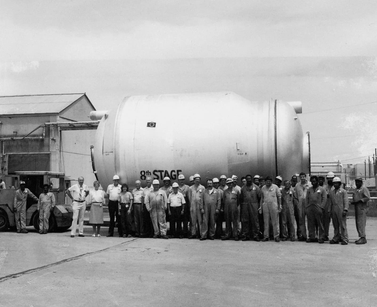 Black-and-white photo of workers standing beside a giant converter at the Paducah Gaseous Diffusion Plant